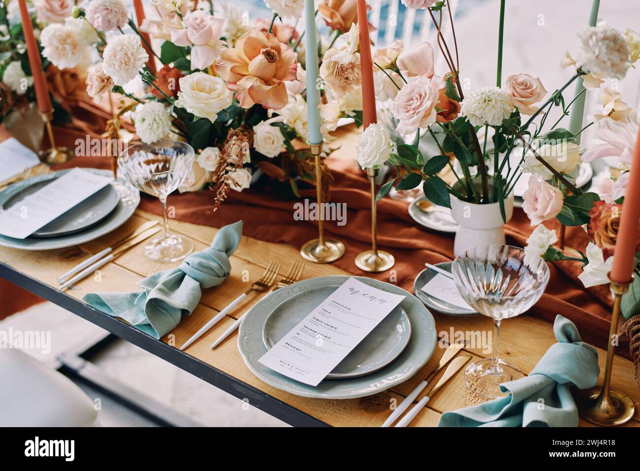 Blumensträuße stehen auf dem Tisch neben dem festlichen Menü auf Tellern Stockfoto