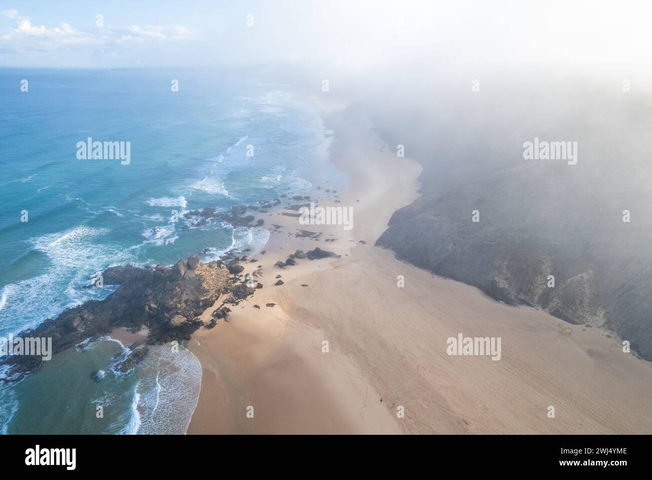 Wellen des Atlantiks an der Küste, Sandstrand und dramatische Klippen in Portugal. Drohnenansicht aus der Luft Stockfoto