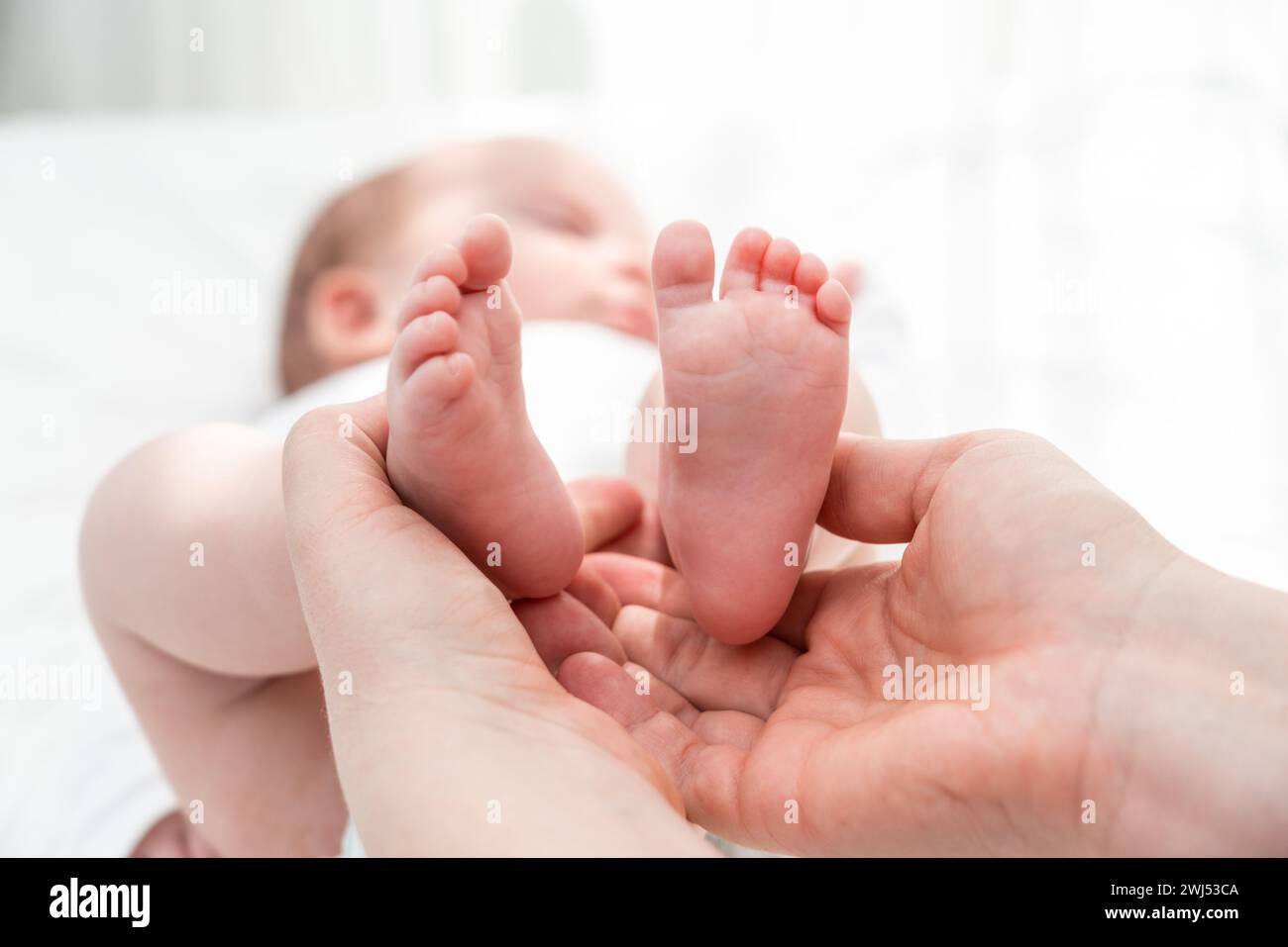 Die kleinen Füße des Neugeborenen mit Sorgfalt gehalten, Konzept der Schutzumarmung der Mutter Stockfoto