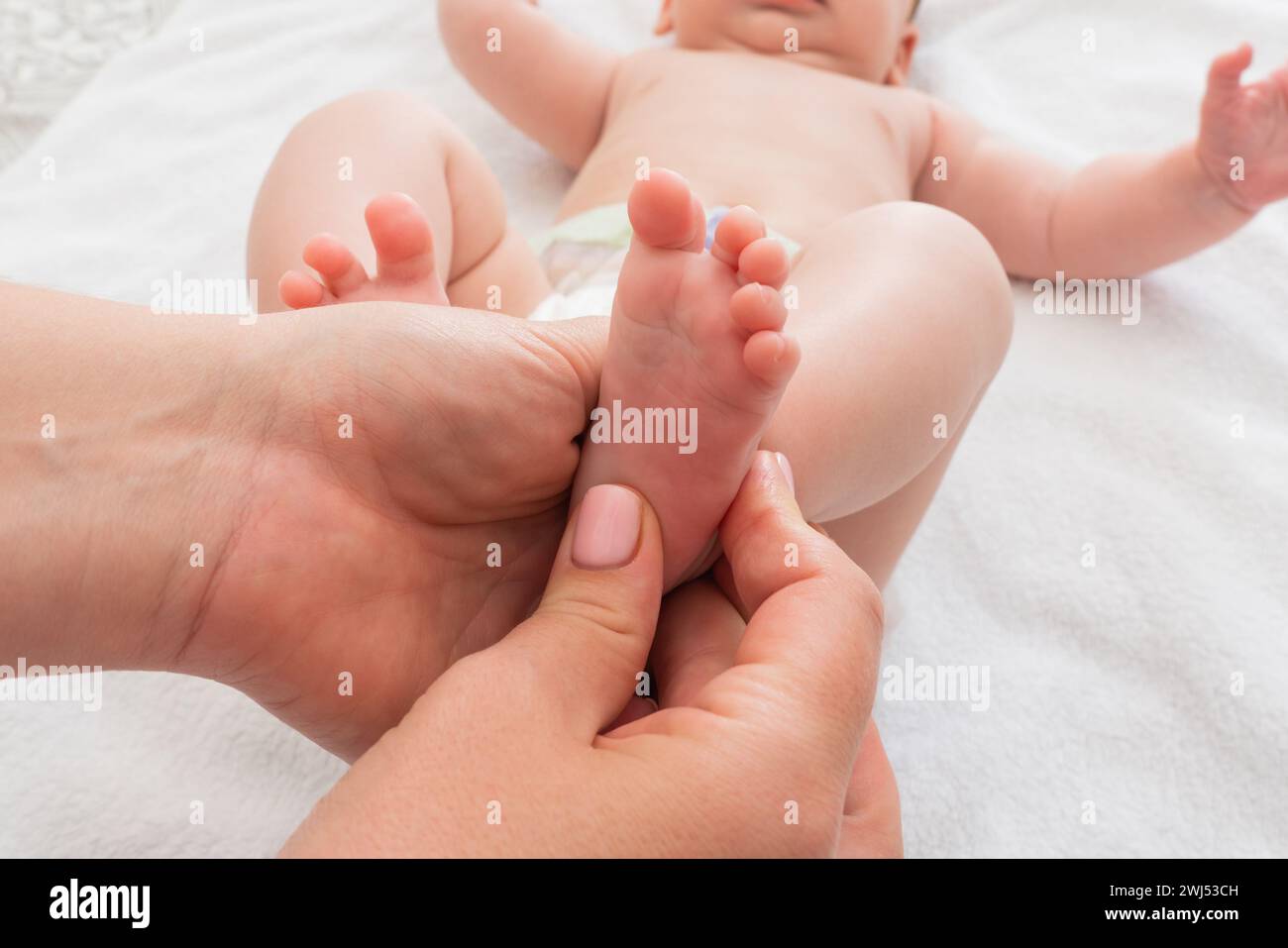 Mutter massiert die winzigen Füße ihres Kindes, Konzept der Pflege und Pflege Stockfoto