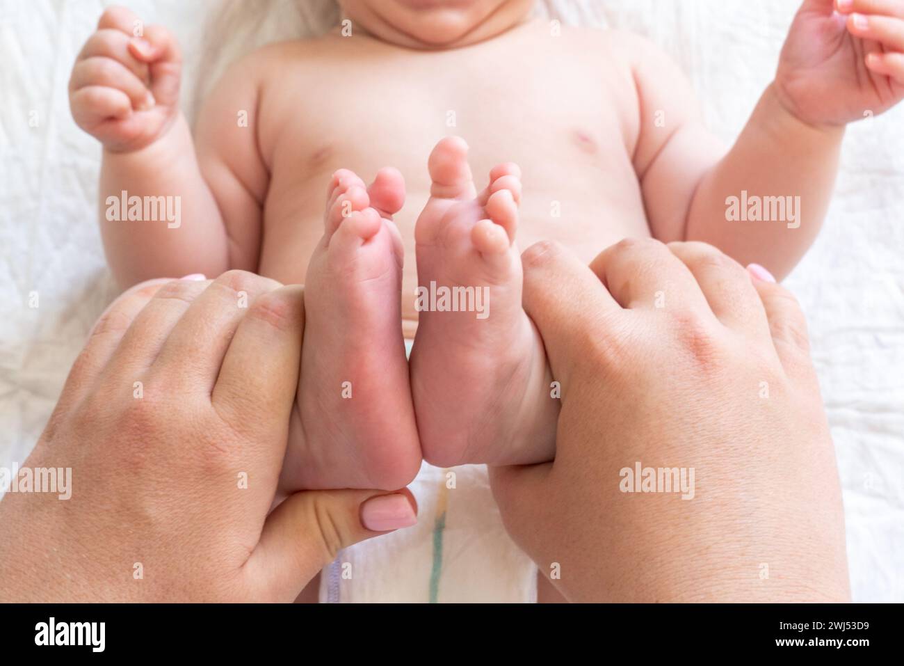 Massagezeit für die winzigen Füße des Neugeborenen, Konzept der heilenden Berührung der Mutter Stockfoto