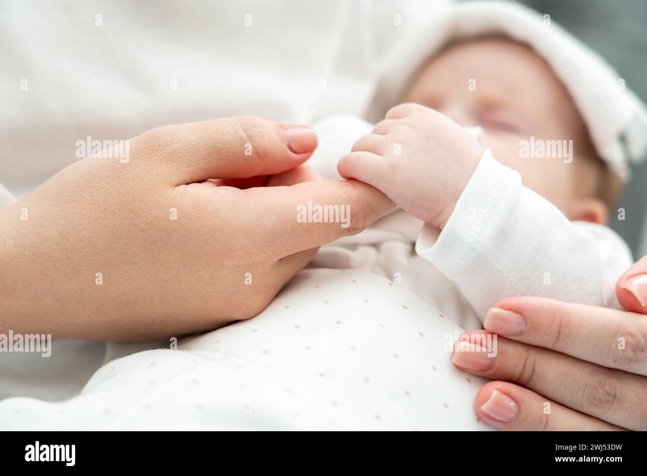 Das Neugeborene findet Trost, den Finger der Mutter während der Krankheit zu halten. Das Konzept des mütterlichen Komforts in der Belastungszeit Stockfoto