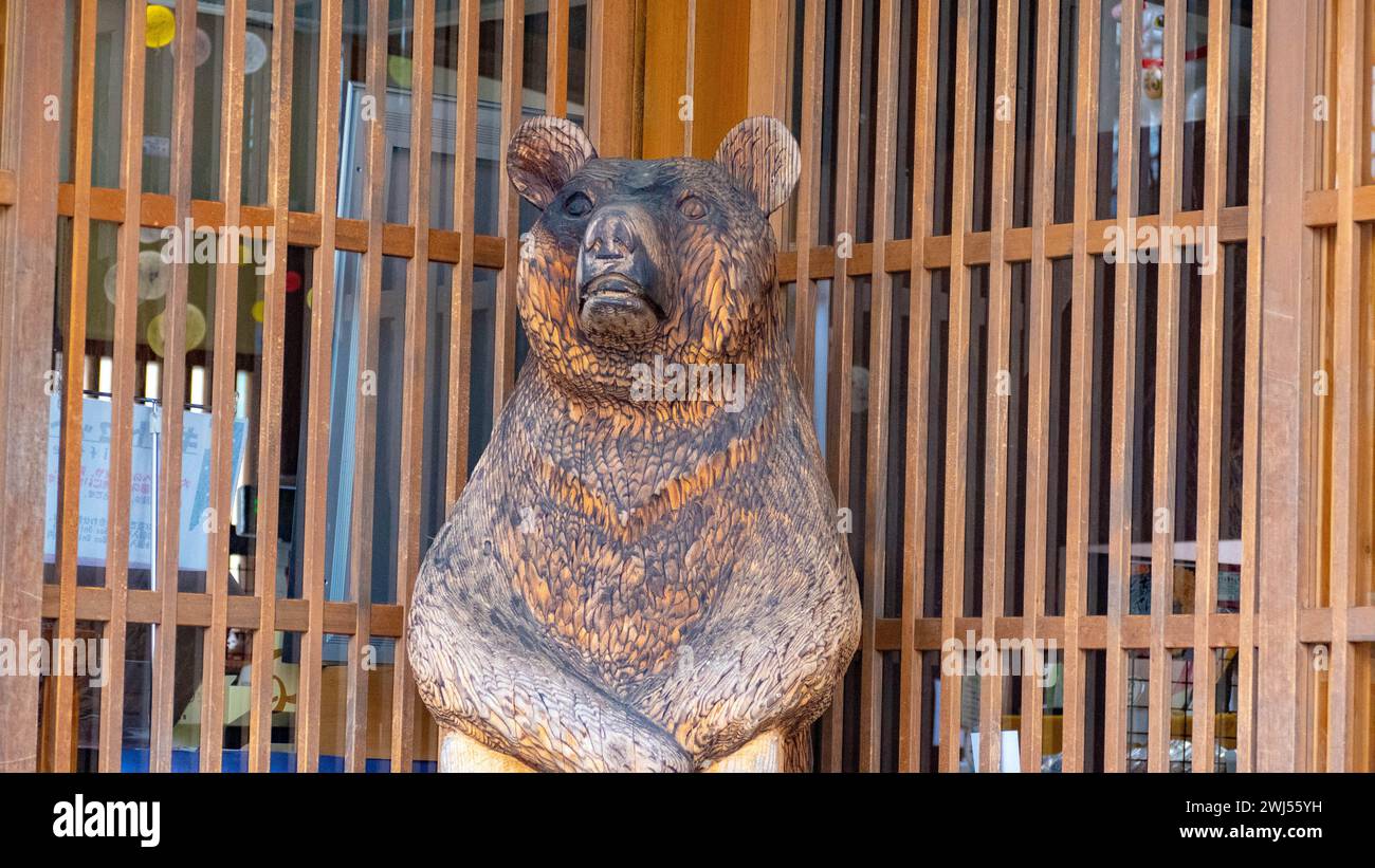 Eine hölzerne Bärenstatue in einem Glaskasten neben dem Fenster in einem japanischen Dorf Stockfoto