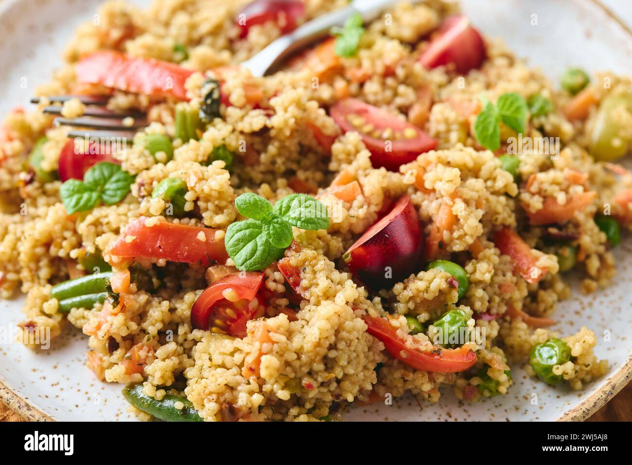 Veganer warmer Salat mit Couscous, Tomaten, grünen Bohnen, Minze, gerösteten Karotten und süßen Paprika. Couscous mit Gemüse, c Stockfoto