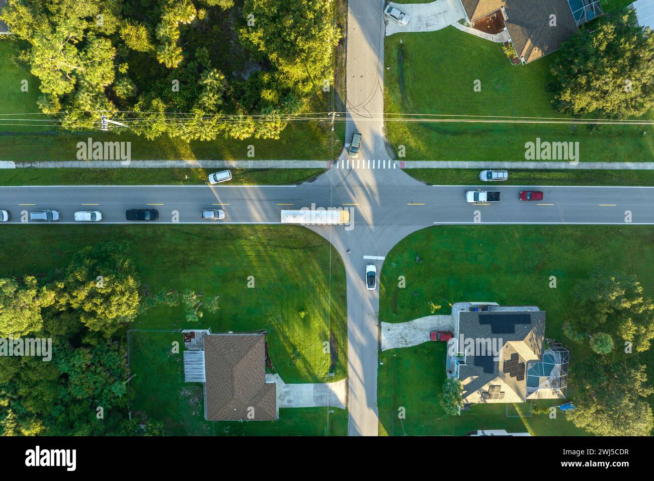 Draufsicht auf den klassischen gelben schulbus der usa, der auf der Straße der ländlichen Stadt fährt, um Kinder für ihre kleinen Kinder am frühen Morgen abzuholen. Öffentlich Stockfoto