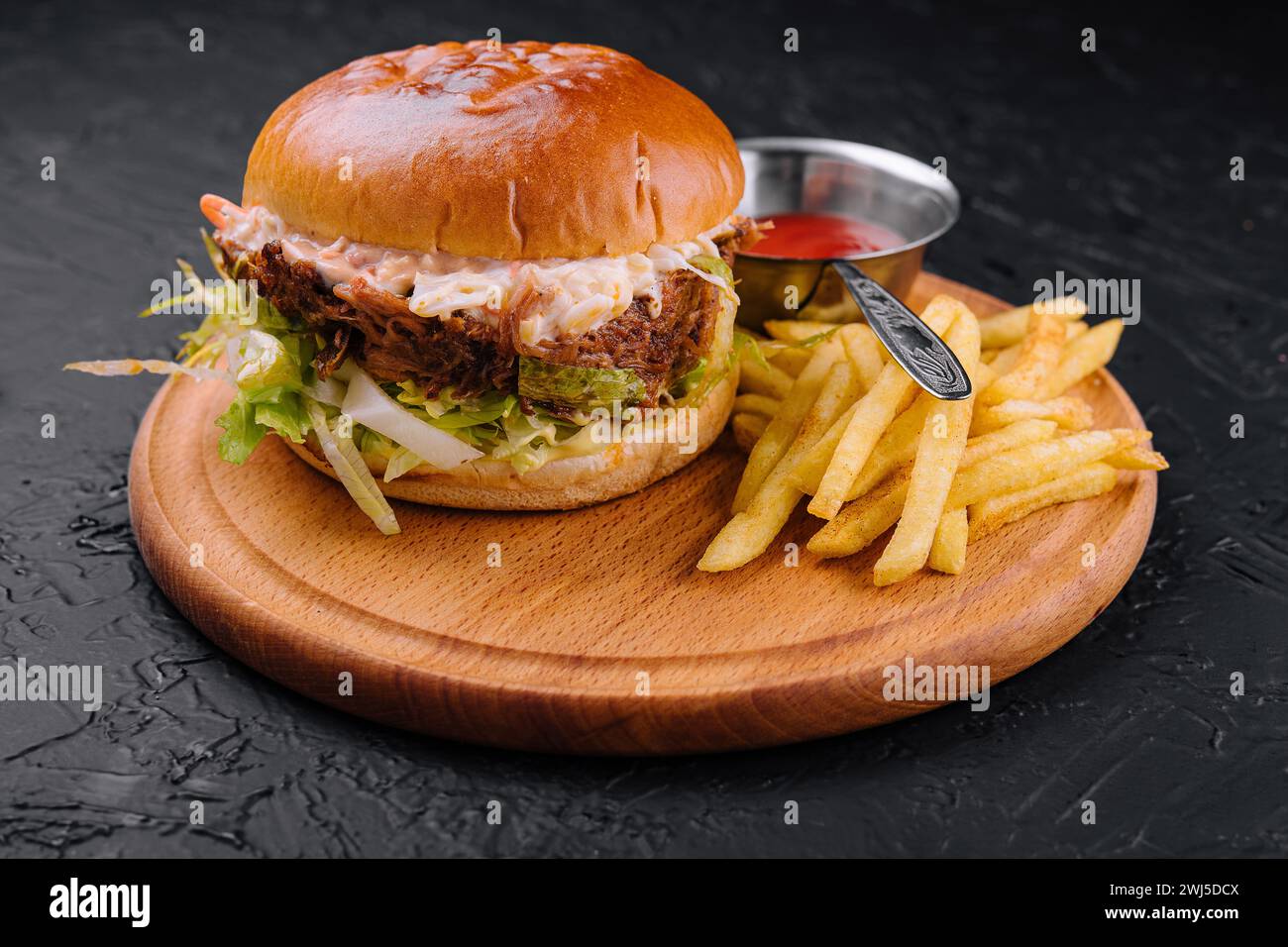 Köstlicher Hamburger mit Käsesauce und Pommes Frites auf Holztisch Stockfoto
