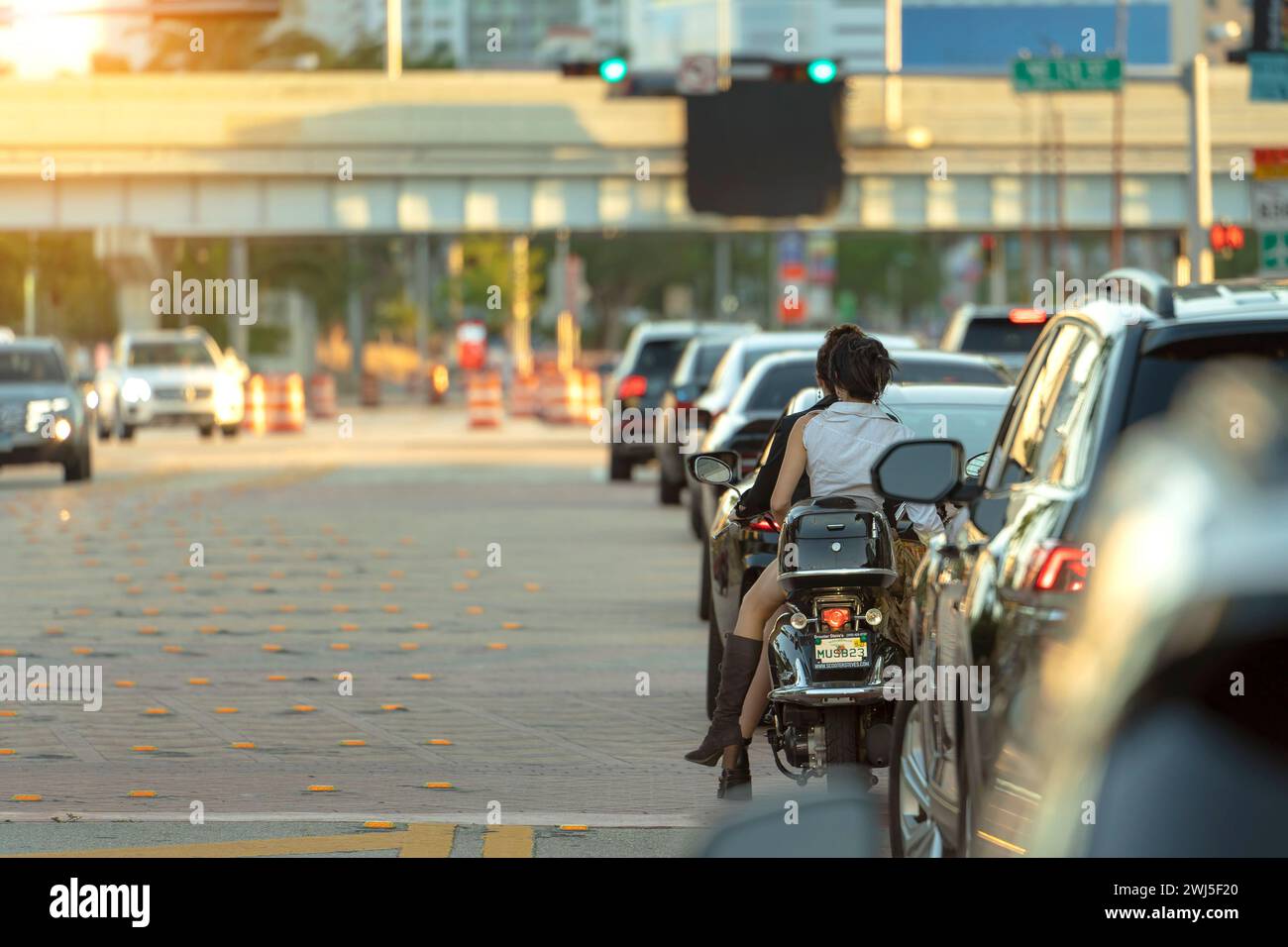 Straßenverkehr in Miami mit fahrendem Motorrad und Autos an der städtischen Kreuzung mit Ampeln in Florida. Stockfoto
