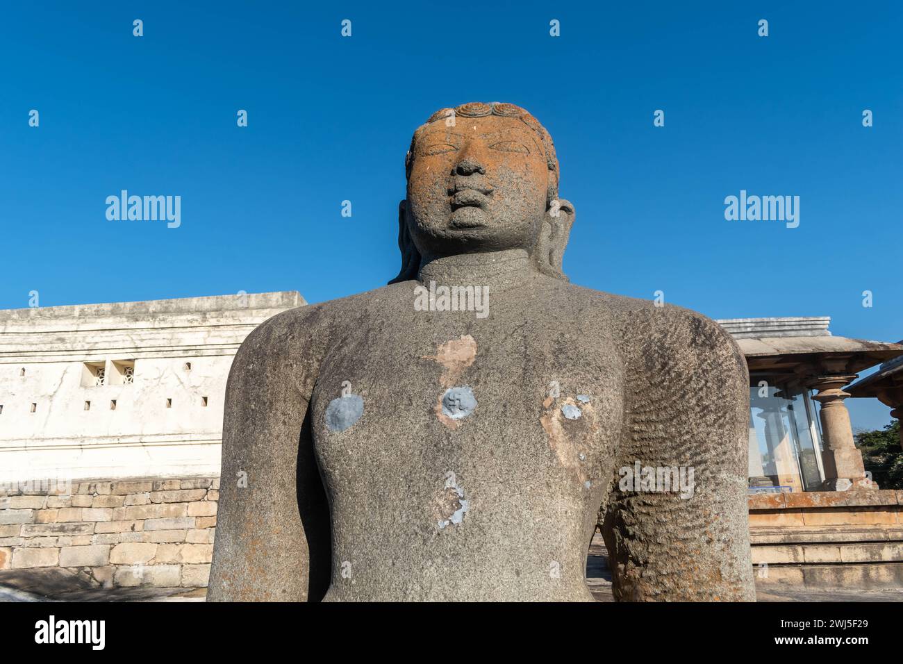Shravanabelagola, Karnataka, Indien - 11. Januar 2023: Die majestätische Statue von Gommateshwara Bahubali steht vor einem klaren blauen Himmel, umgeben von anc Stockfoto