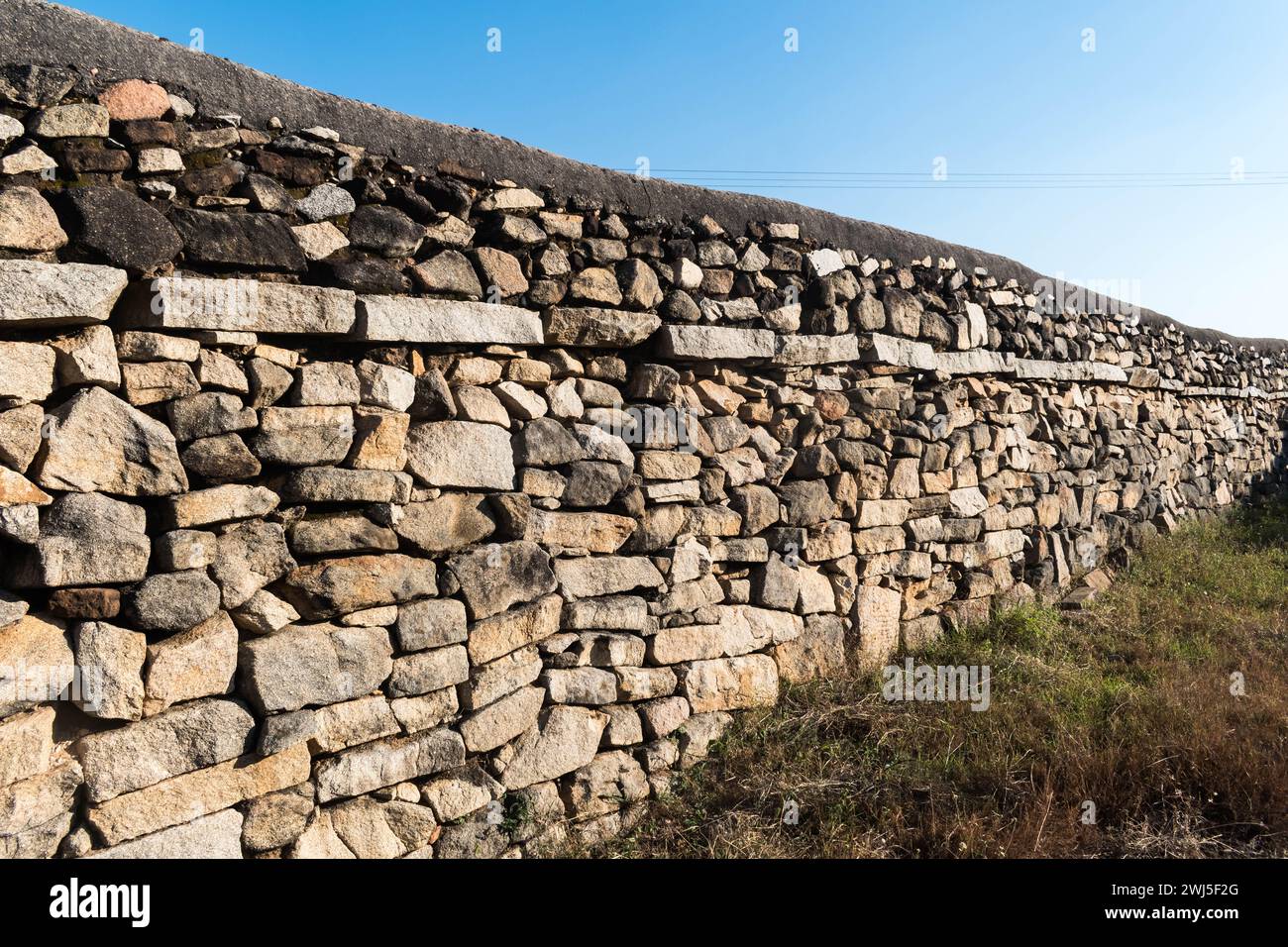 Das Foto zeigt die detaillierte Textur einer alten Steinmauer in Shravanabelagola, die sich in der Wärme eines sonnigen Tages sonnt. Stockfoto