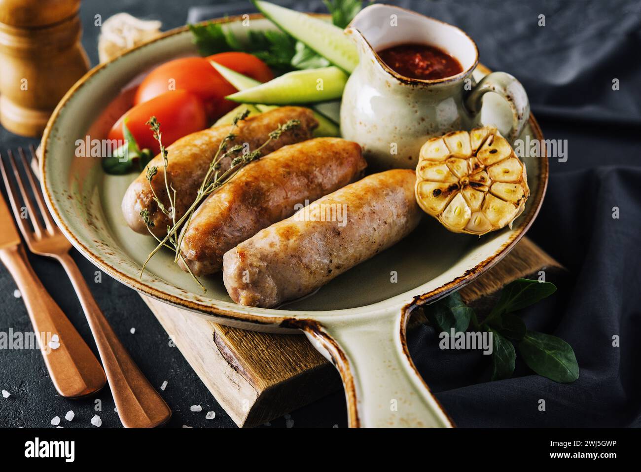 Gebratene Würstchen mit Kräutern und Gemüse in der Pfanne Stockfoto