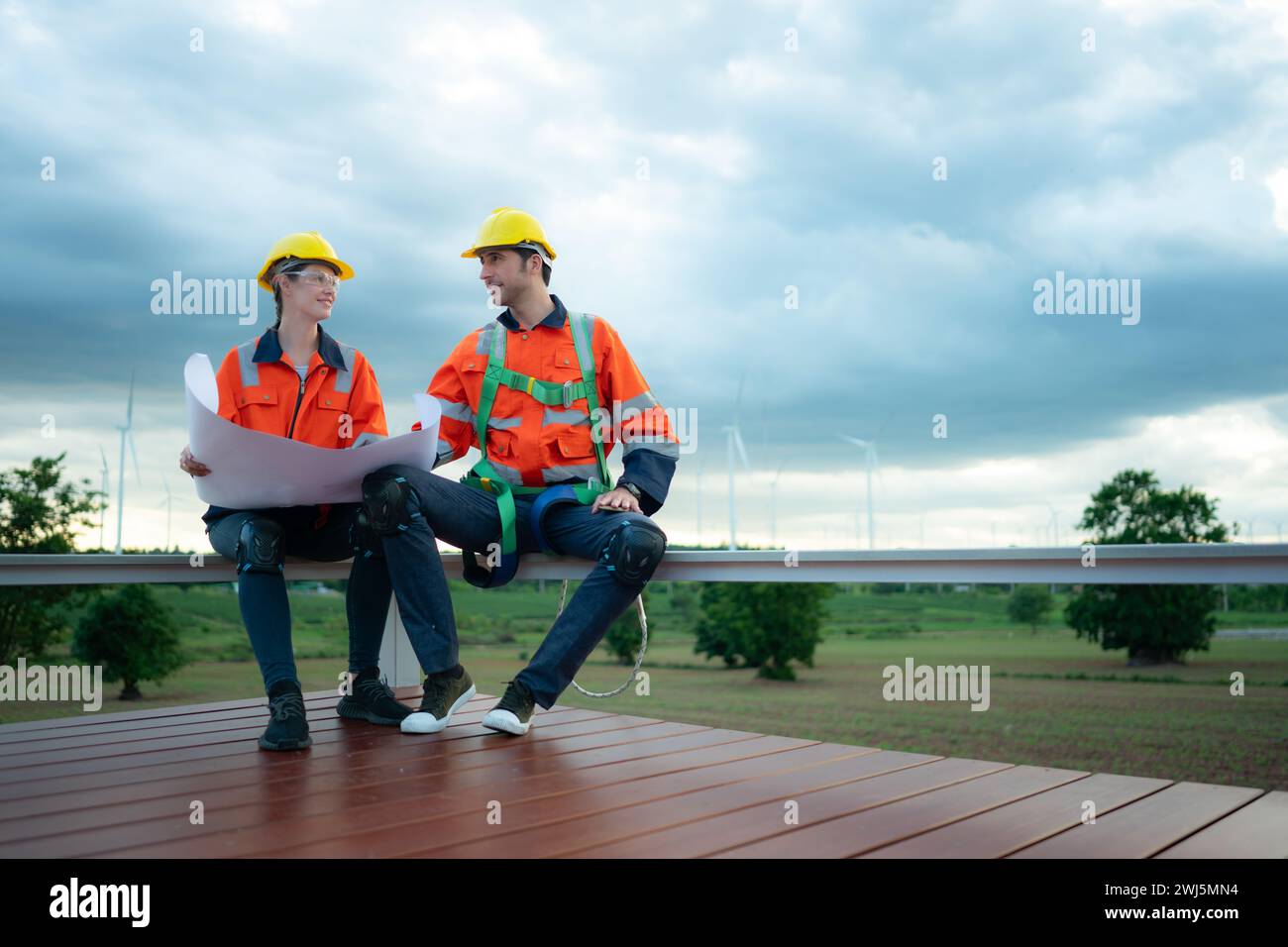 Ingenieur und Techniker besprechen den Plan auf der Baustelle mit Windkraftanlagen-Hintergrund Stockfoto