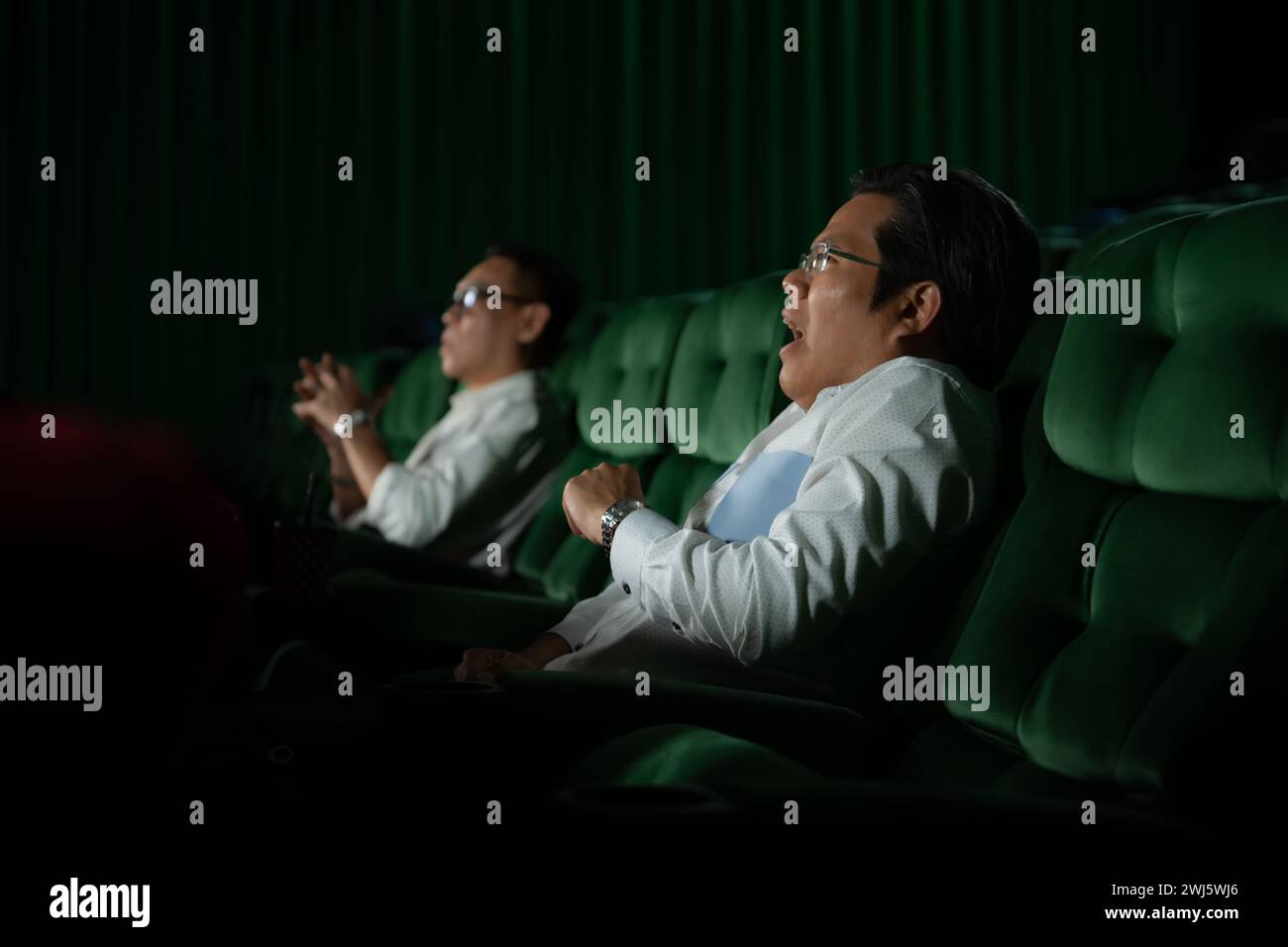 Ein junges Paar, das sich im Kino Filme anschaut und auf den grünen Sitzen sitzt. Stockfoto