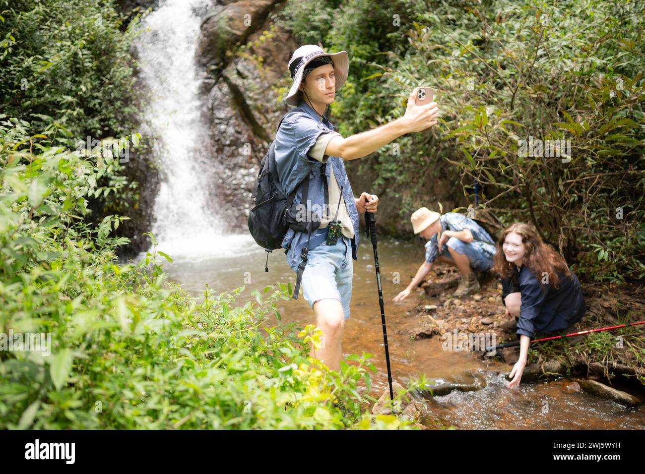 Mann und Frau Wanderer, die sich am Wasserfall im Wald fotografieren Stockfoto