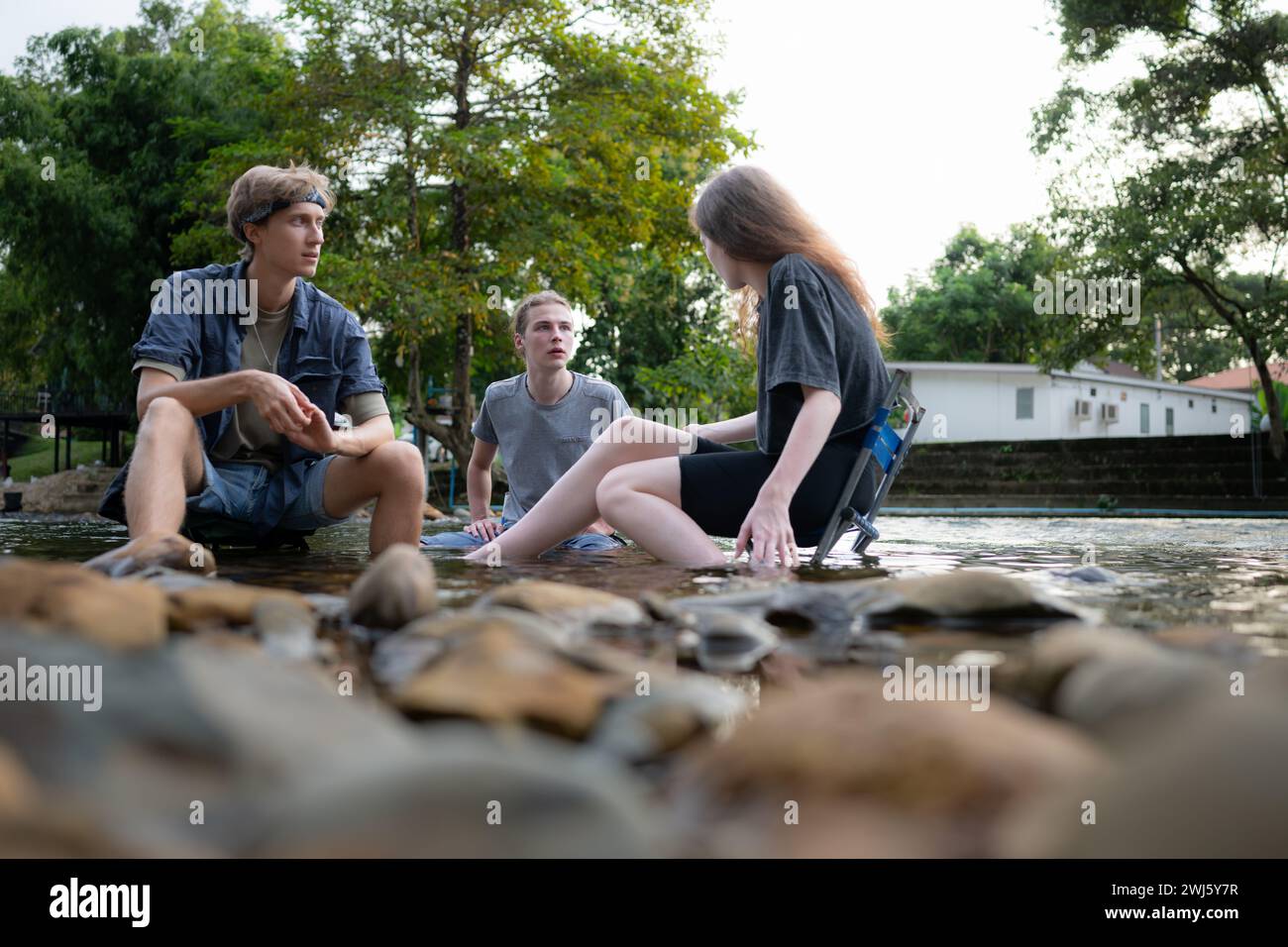 Eine Gruppe von Freunden unterhält sich und hat Spaß in der Mitte des Flusses, der vor dem Campingplatz fließt. Stockfoto