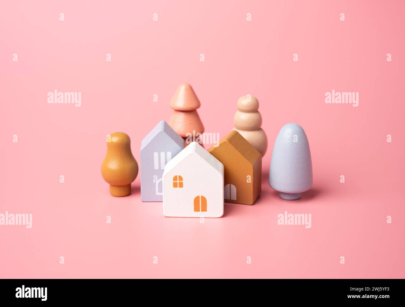 Häuser und Baumfiguren auf rosafarbenem Hintergrund. Erschwingliche Wohnungen. Ich kaufe ein schönes Haus. Garten, Landschaftsdesign. Figur. Hypotheken und Darlehen. Stockfoto