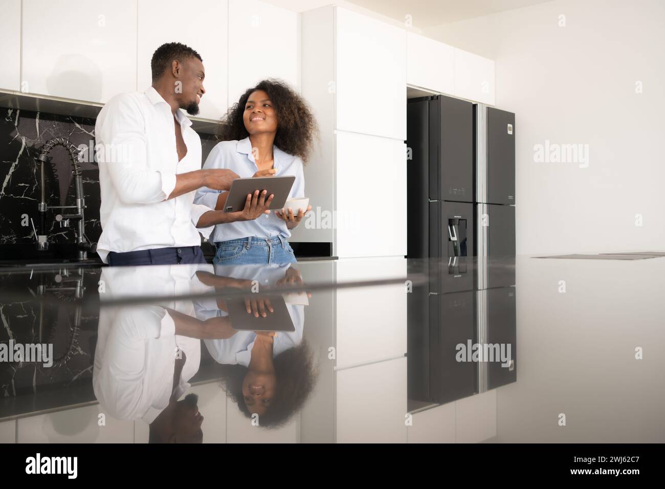 Beide junge Paare diskutieren mit Laptops in der Küche zu Hause über Geschäfte. Stockfoto