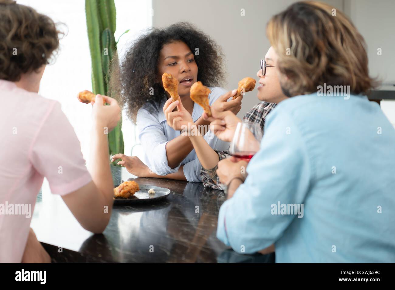 Gruppe junger Freunde, die zu Hause Fast Food essen. Multiethnische Gruppe von Menschen, die zusammen zu Mittag essen. Kommunikationskonzept Stockfoto