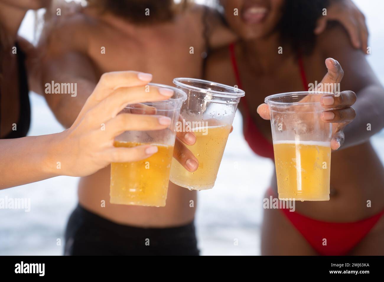 Multi-ethnische Gruppe von Freunden, die Spaß am Strand haben, Bier trinken und Spaß haben Stockfoto