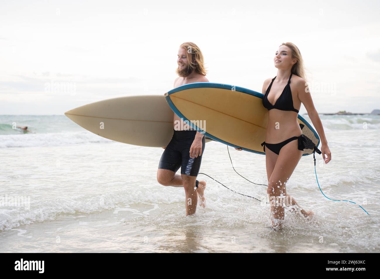 Junger Mann und Frau, die Surfbretter halten, um ins Meer zu gehen, um zu surfen. Stockfoto