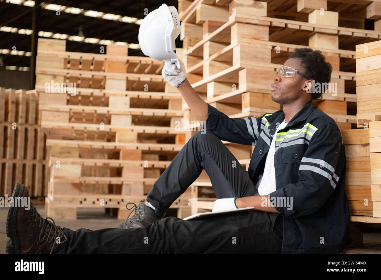 Junge Arbeiter arbeiten in einer Holzfabrik, lehnen Sie sich zurück und entspannen Sie sich, nachdem Sie die Holzdielen überprüft haben Stockfoto