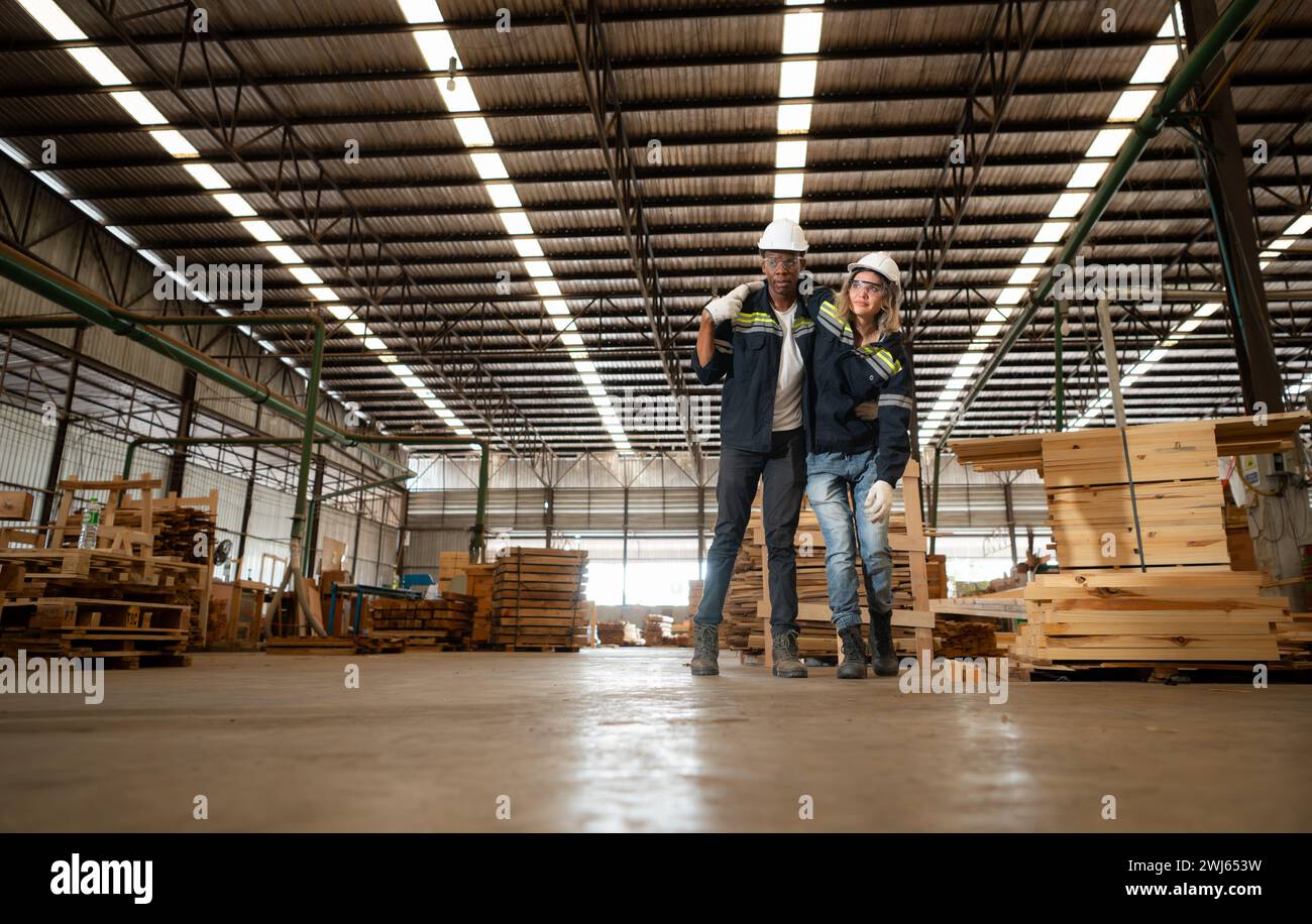 Arbeiter im Holzlager verletzt am Bein, Kollegen helfen und unterstützen, in den erste-Hilfe-Raum zur Behandlung zu gehen. Stockfoto