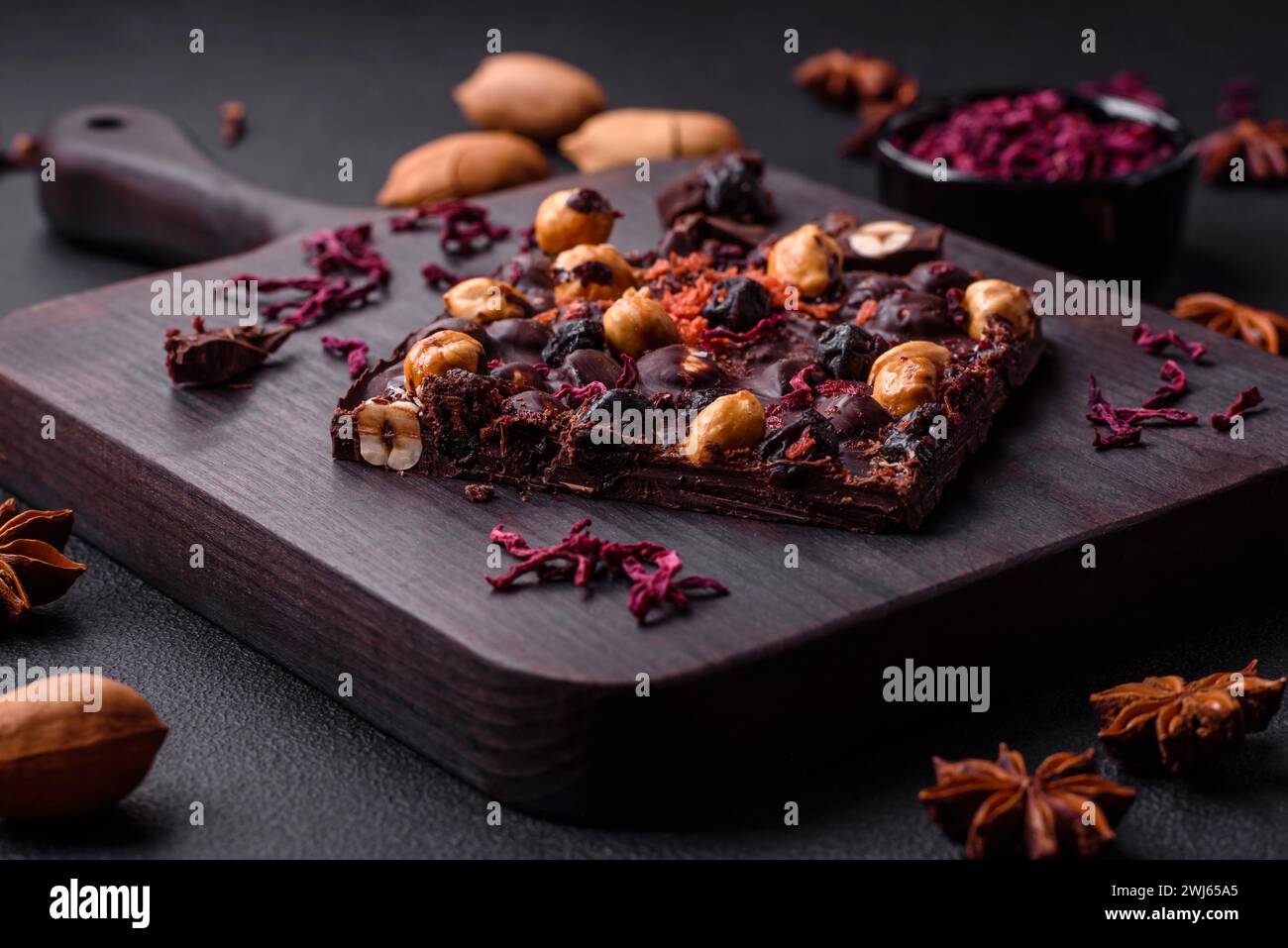 Handgemachte Schokolade mit Beeren, Nüssen und Gewürzen auf dunklem Hintergrund Stockfoto