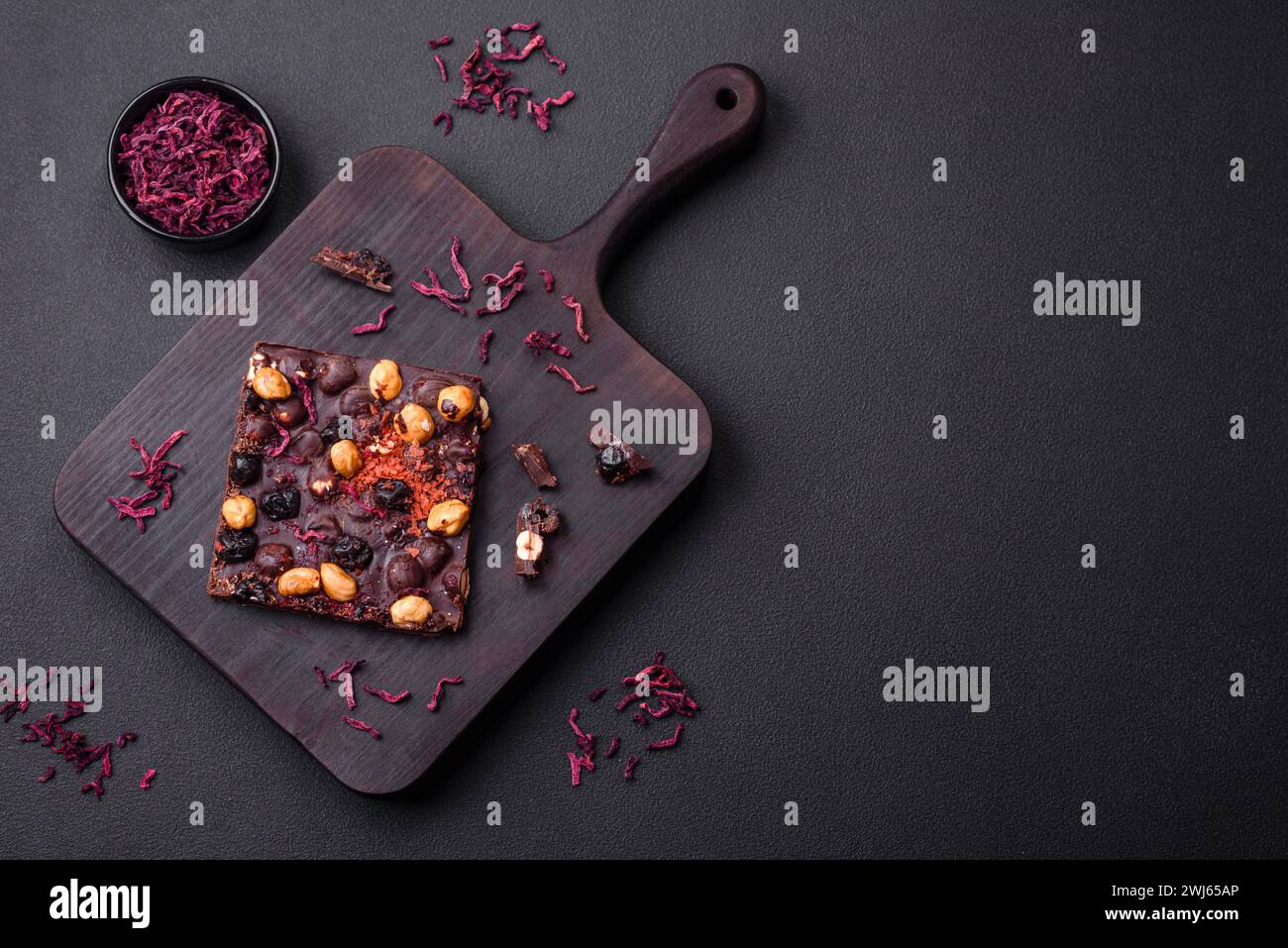 Handgemachte Schokolade mit Beeren, Nüssen und Gewürzen auf dunklem Hintergrund Stockfoto