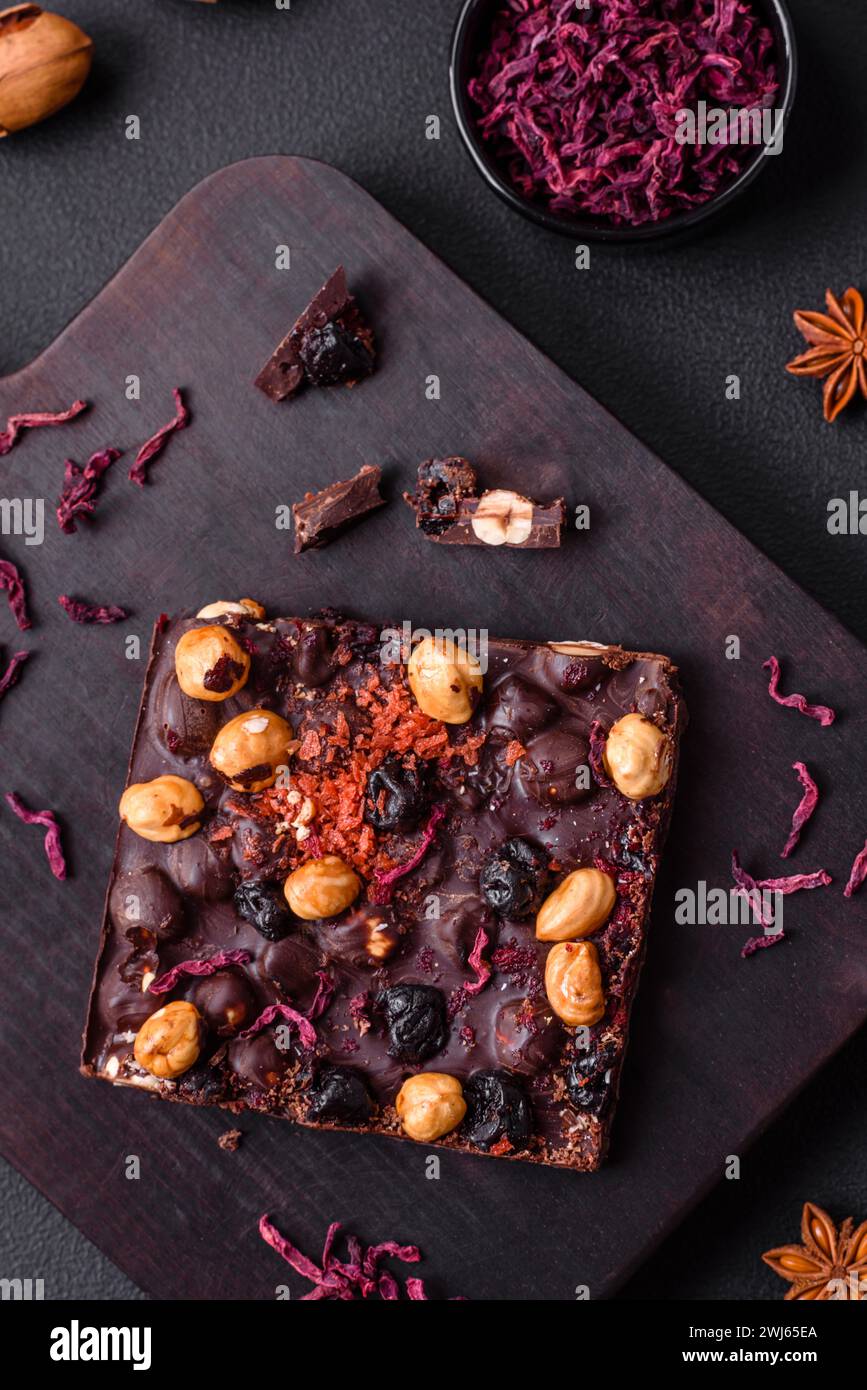 Handgemachte Schokolade mit Beeren, Nüssen und Gewürzen auf dunklem Hintergrund Stockfoto