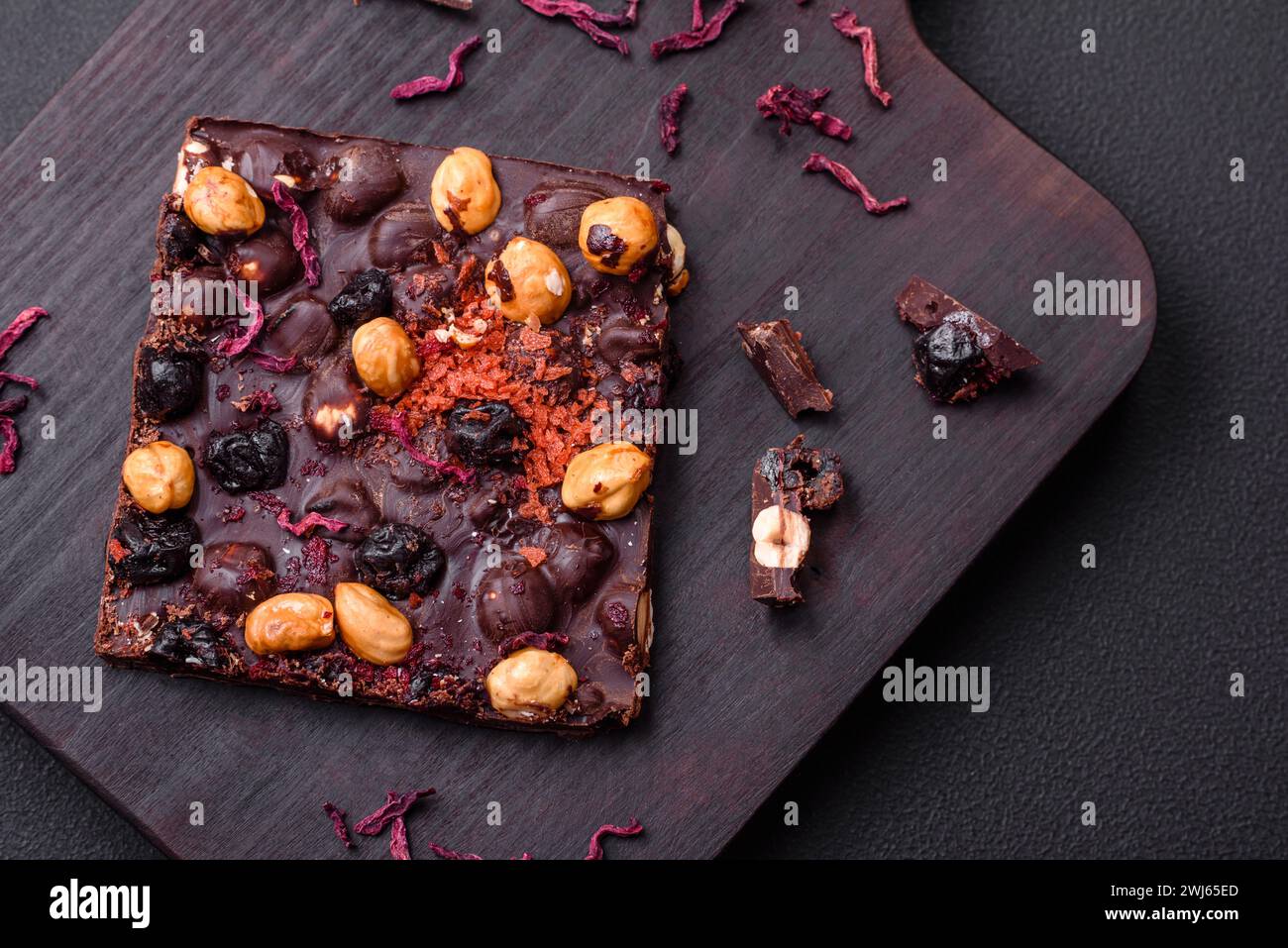 Handgemachte Schokolade mit Beeren, Nüssen und Gewürzen auf dunklem Hintergrund Stockfoto