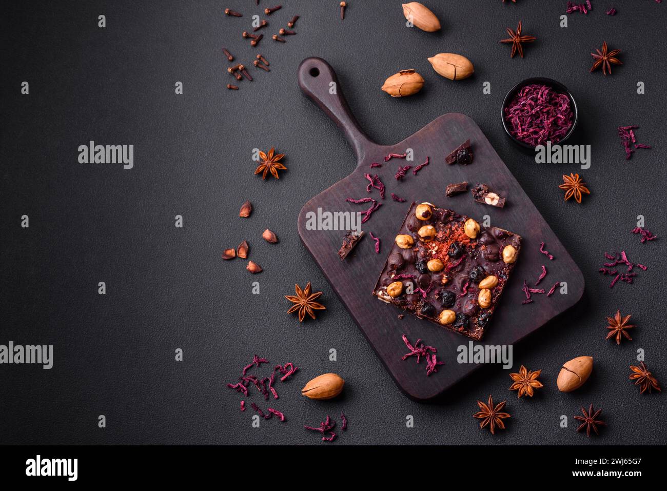 Handgemachte Schokolade mit Beeren, Nüssen und Gewürzen auf dunklem Hintergrund Stockfoto