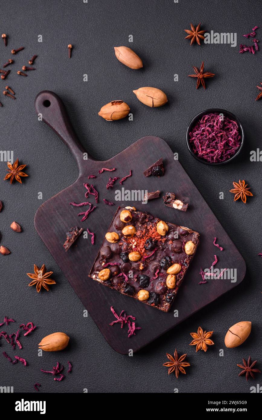 Handgemachte Schokolade mit Beeren, Nüssen und Gewürzen auf dunklem Hintergrund Stockfoto