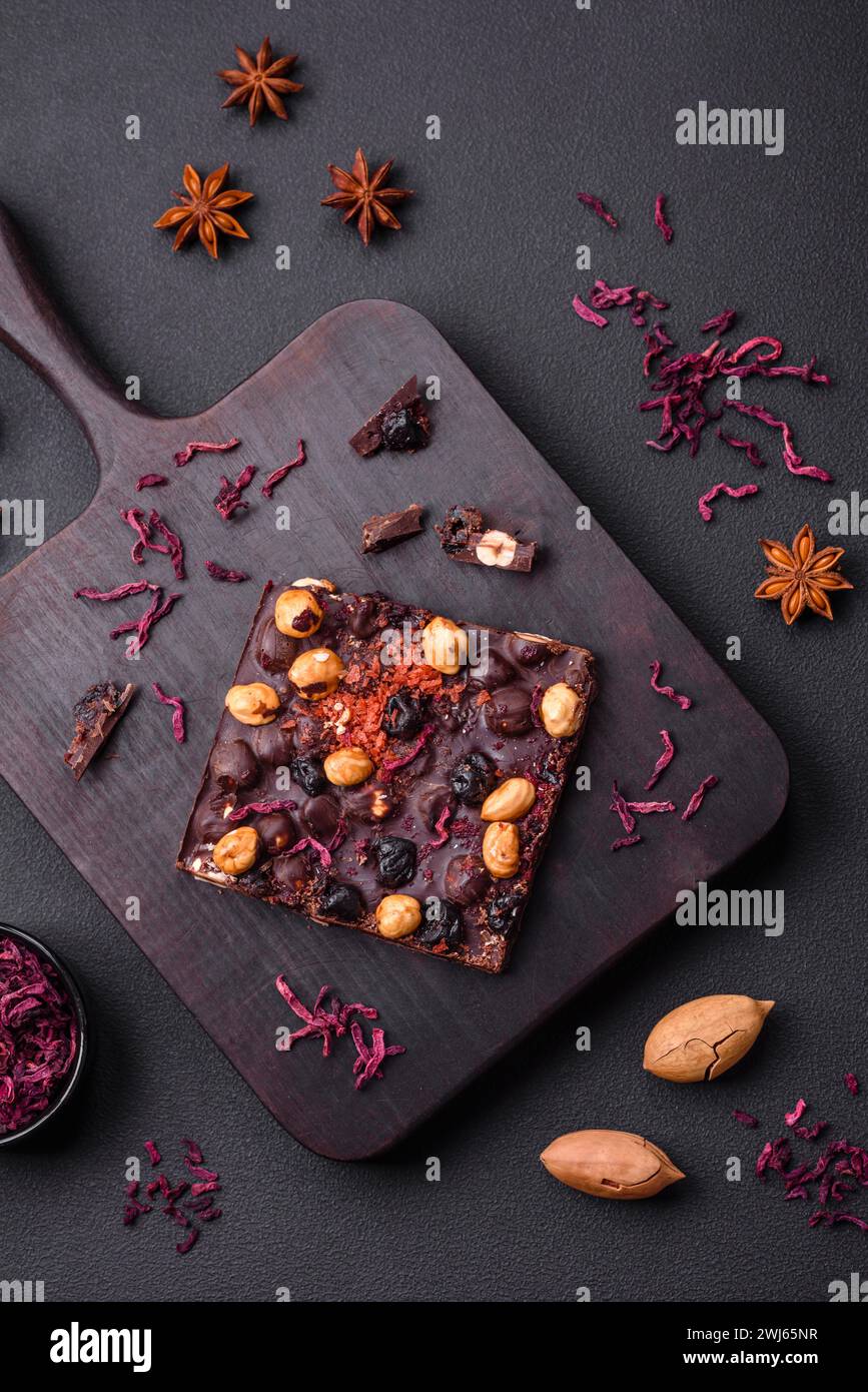 Handgemachte Schokolade mit Beeren, Nüssen und Gewürzen auf dunklem Hintergrund Stockfoto