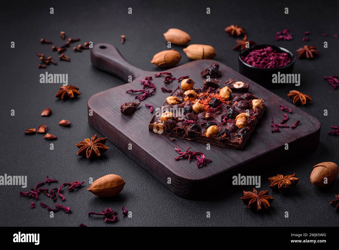 Handgemachte Schokolade mit Beeren, Nüssen und Gewürzen auf dunklem Hintergrund Stockfoto