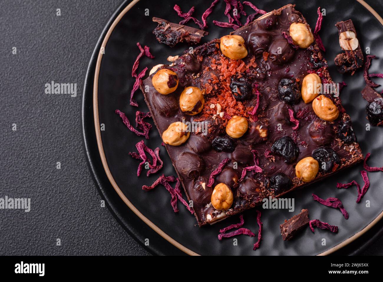 Handgemachte Schokolade mit Beeren, Nüssen und Gewürzen auf dunklem Hintergrund Stockfoto
