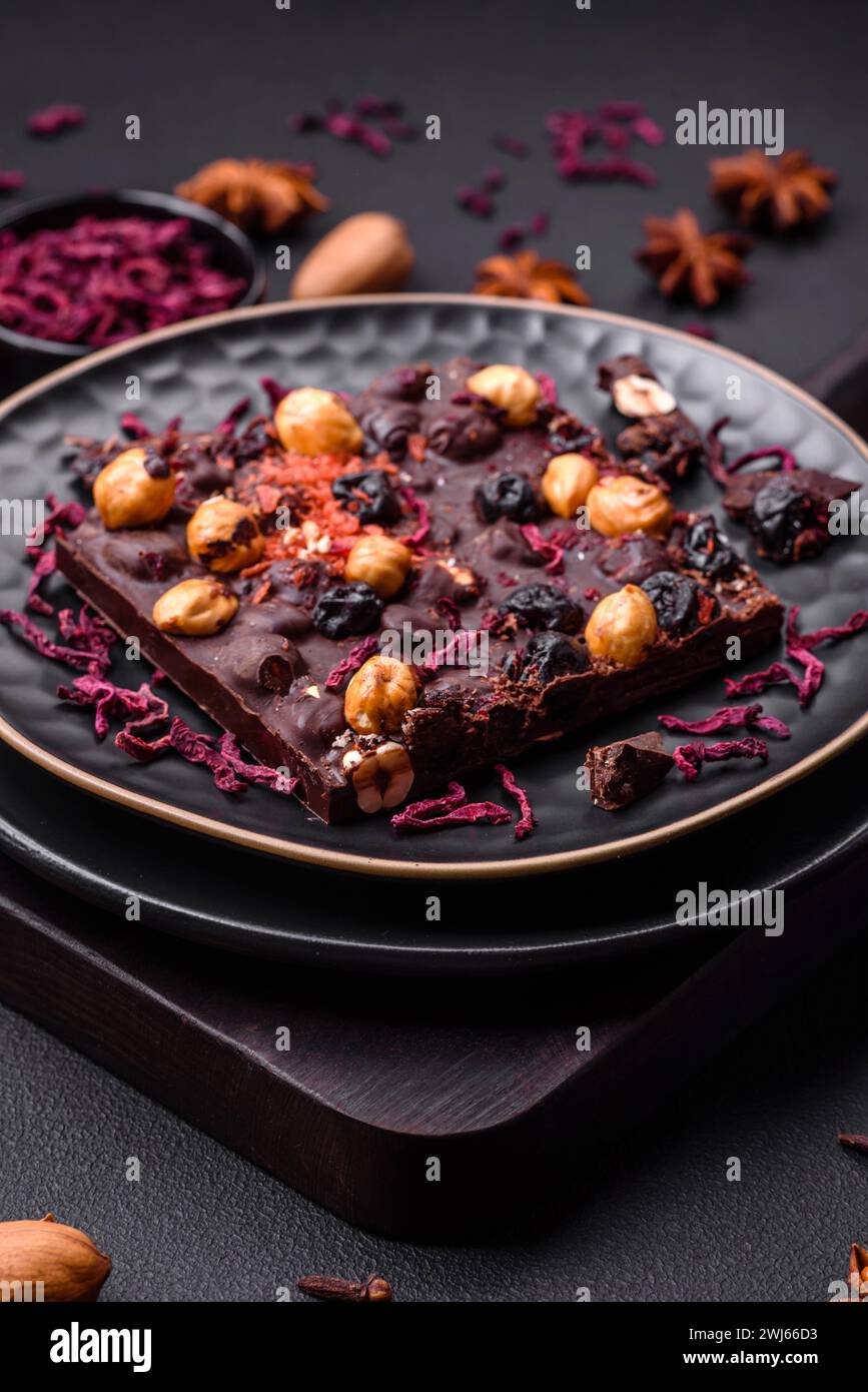Handgemachte Schokolade mit Beeren, Nüssen und Gewürzen auf dunklem Hintergrund Stockfoto