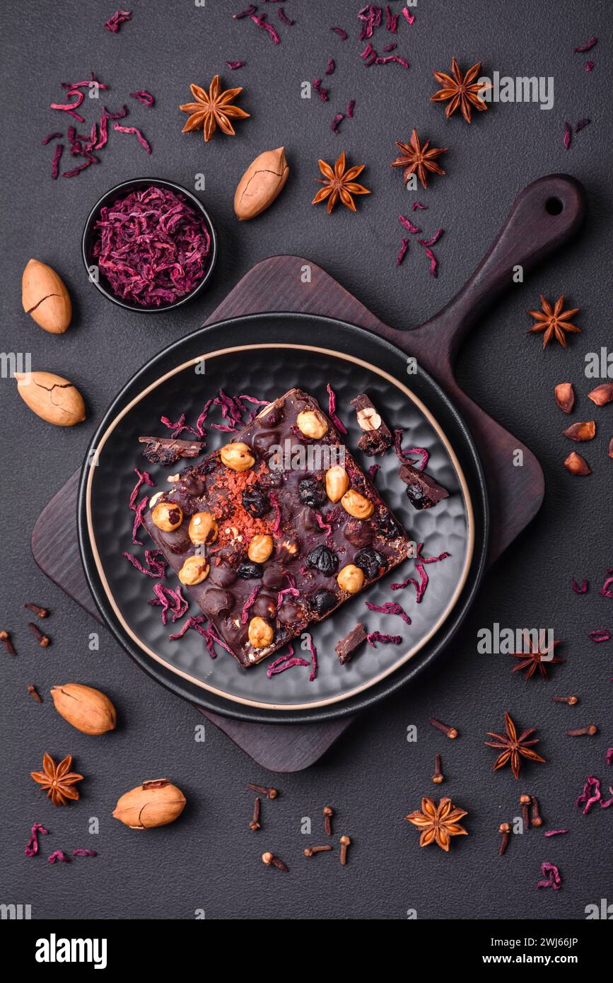 Handgemachte Schokolade mit Beeren, Nüssen und Gewürzen auf dunklem Hintergrund Stockfoto