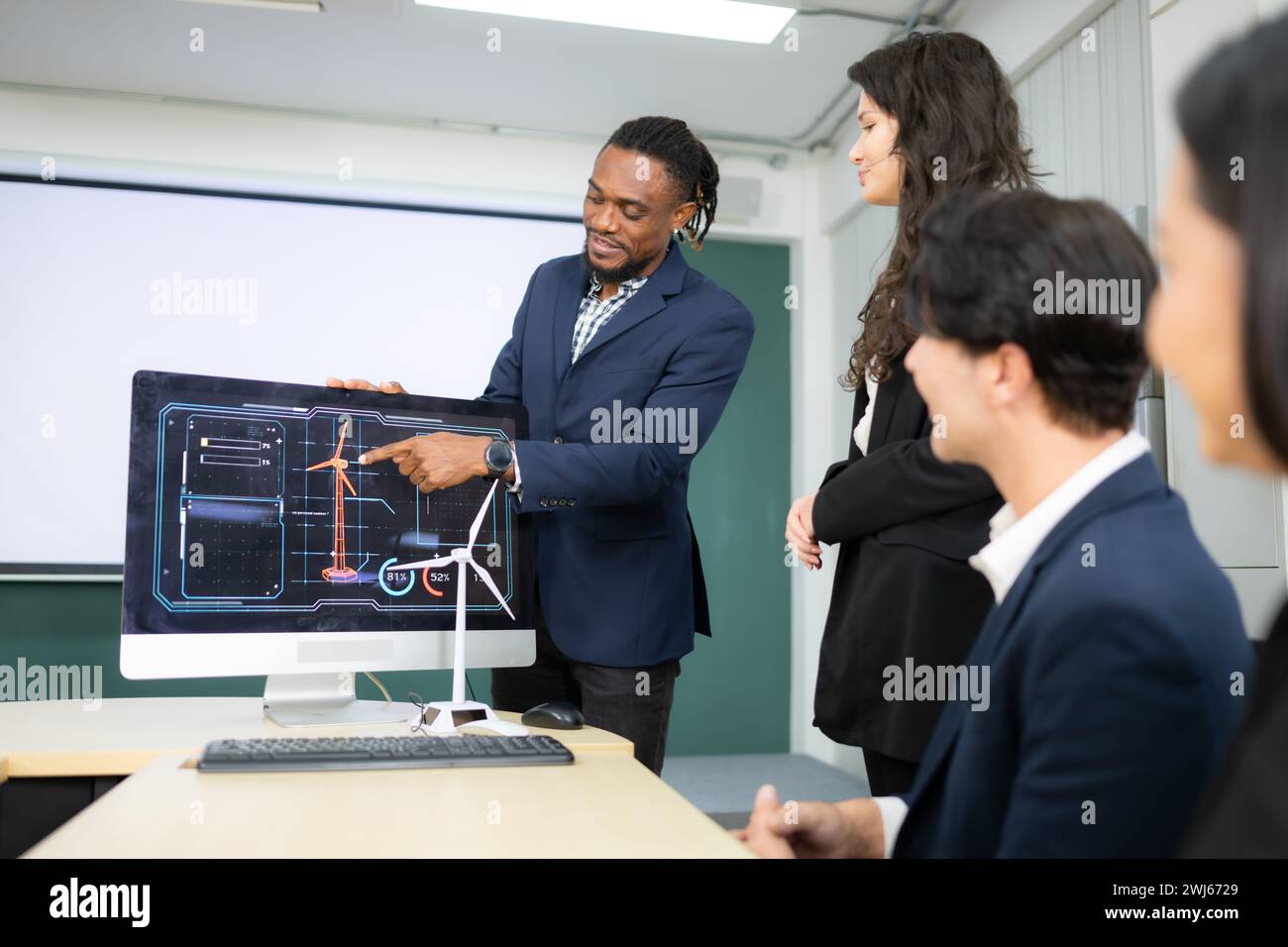 Ein breites Team von Geschäftsleuten und Ingenieuren berät bei der Entwicklung einer Windkraftanlage, die Windenergie in Elektri umwandelt Stockfoto