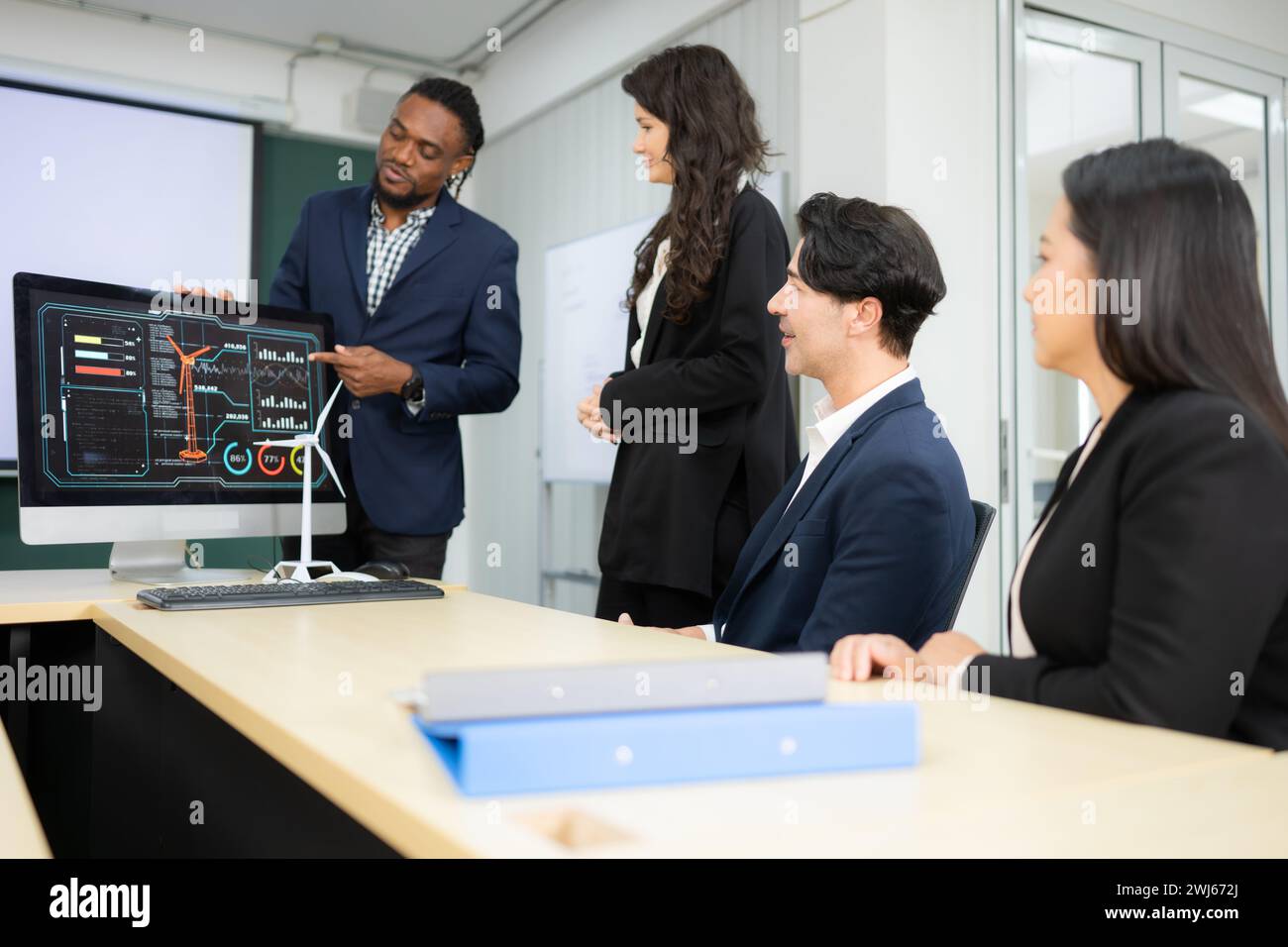 Ein breites Team von Geschäftsleuten und Ingenieuren berät bei der Entwicklung einer Windkraftanlage, die Windenergie in Elektri umwandelt Stockfoto