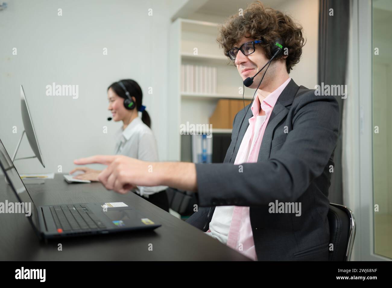 Gruppe von Geschäftsleuten, die ein Headset tragen und aktiv im Büro arbeiten. Callcenter, Telemarketing, Kundendienstmitarbeiter Stockfoto