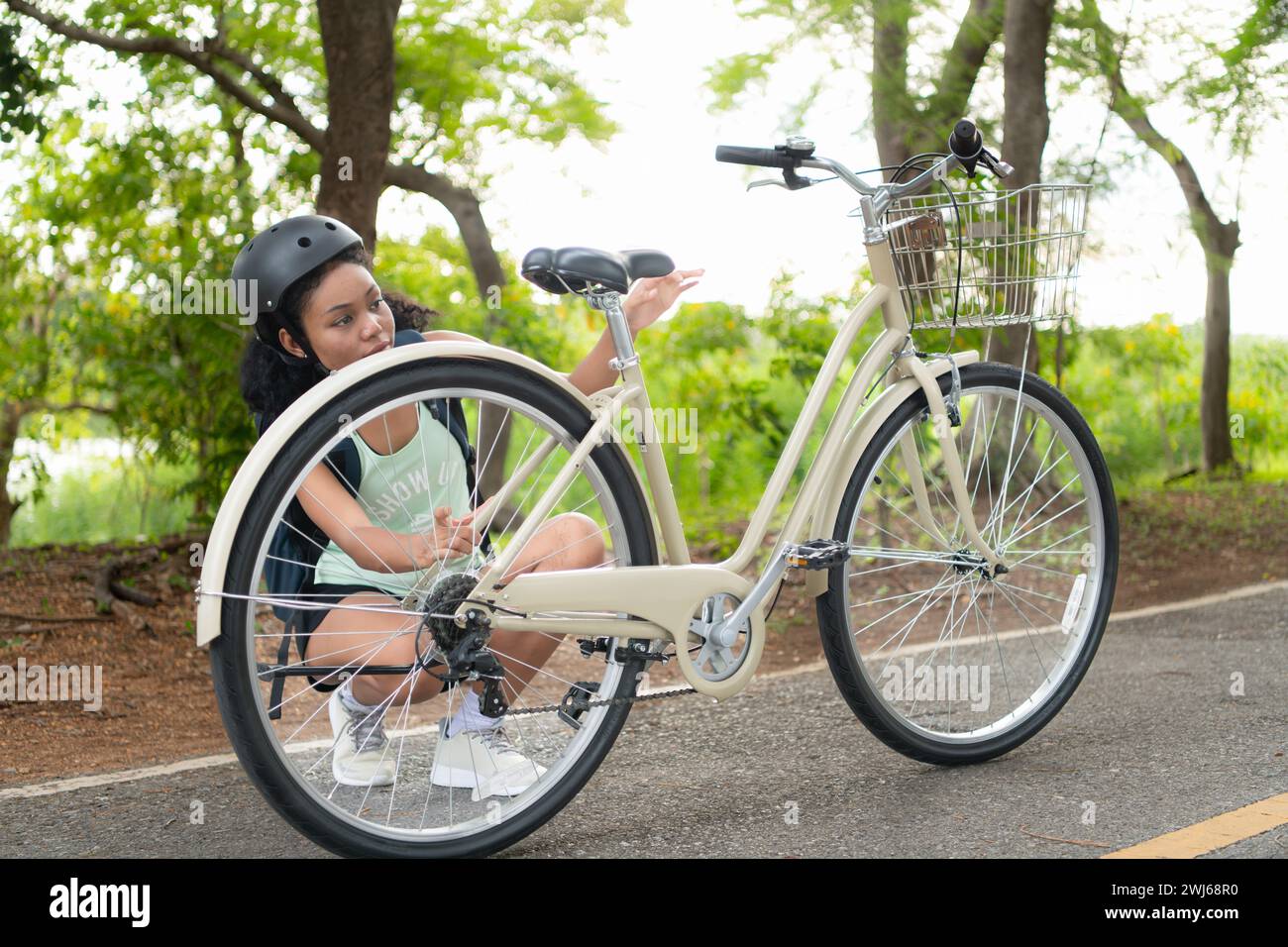Junge Frau mit Rucksack und Solarpanel zum Aufladen des Smartphones. Während sie die Bereitschaft ihres Fahrrads überprüft. Vor der Fahrt Stockfoto