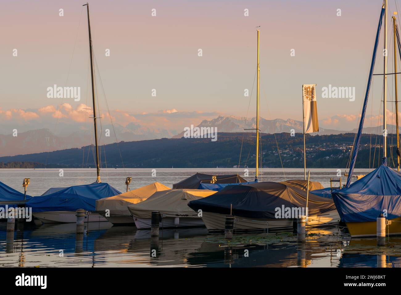 Boote auf einem See, die sich im Wasser spiegeln. Alpen und Nachglühen im Hintergrund. Stockfoto