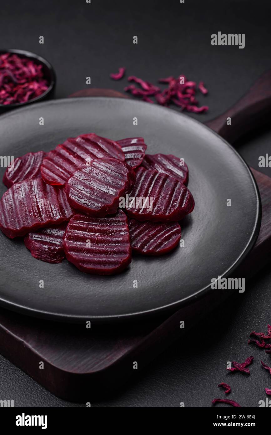 Köstliche gesunde, rubinfarbene Rüben, geschnitten auf einer schwarzen Platte Stockfoto