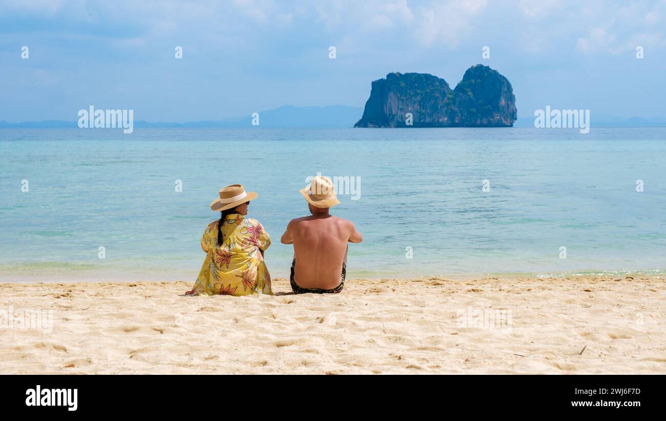 Ein paar Männer und Frauen sitzen am tropischen Strand auf der Insel Koh Ngai Stockfoto