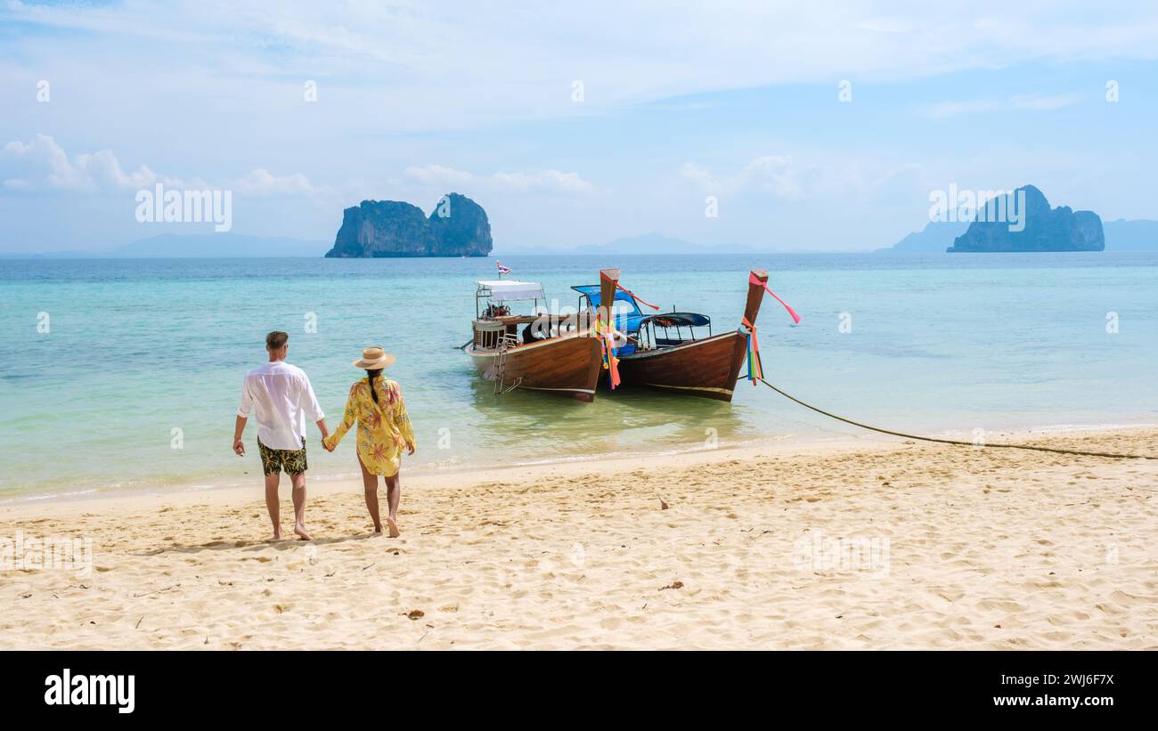 Ein paar Männer und Frauen laufen am Strand mit Longtail-Booten auf der Insel Koh Ngai Thailand Stockfoto