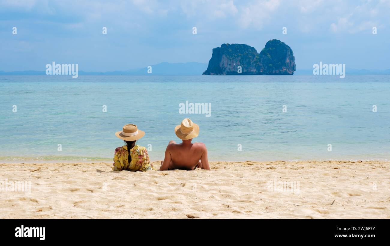 Ein paar Männer und Frauen sitzen am tropischen Strand auf der Insel Koh Ngai Stockfoto