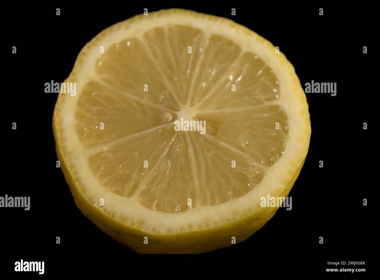 Halbgelbe Zitrone mit dunkelschwarzem Hintergrund, horizontal Citrus aurantifolia Stockfoto