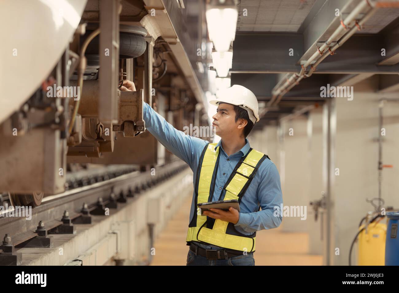 Elektrozugingenieur inspiziert Elektrozugmaschinen mit Tablets gemäß Inspektionsrunde, nachdem der Elektrozug ist Stockfoto