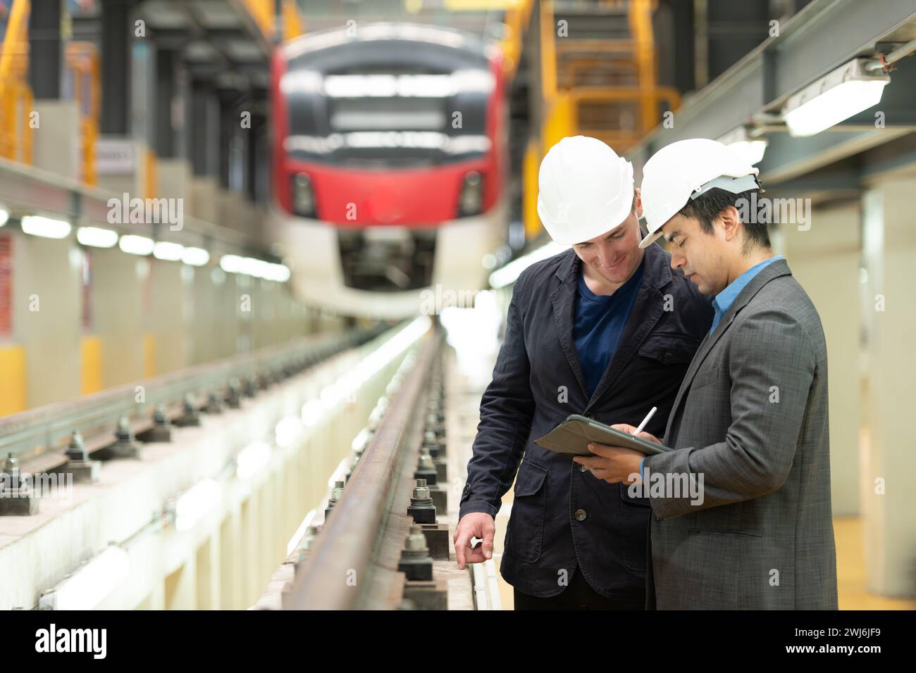 Zwei Geschäftsleute prüfen die Eisenbahnarbeiten, um Ausrüstungen für die Reparatur von Gleisen und Maschinen des elektrischen Zugverkehrs zu reservieren Stockfoto