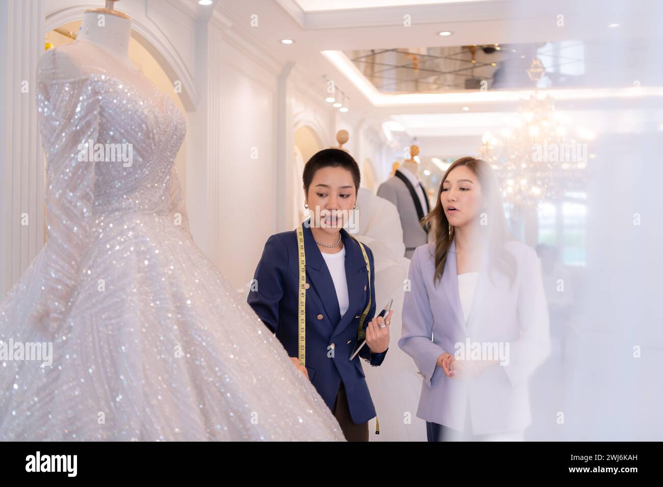 Beide asiatischen Modedesigner arbeiten im Hochzeitskleiderladen mit Hochzeitskleidern Stockfoto