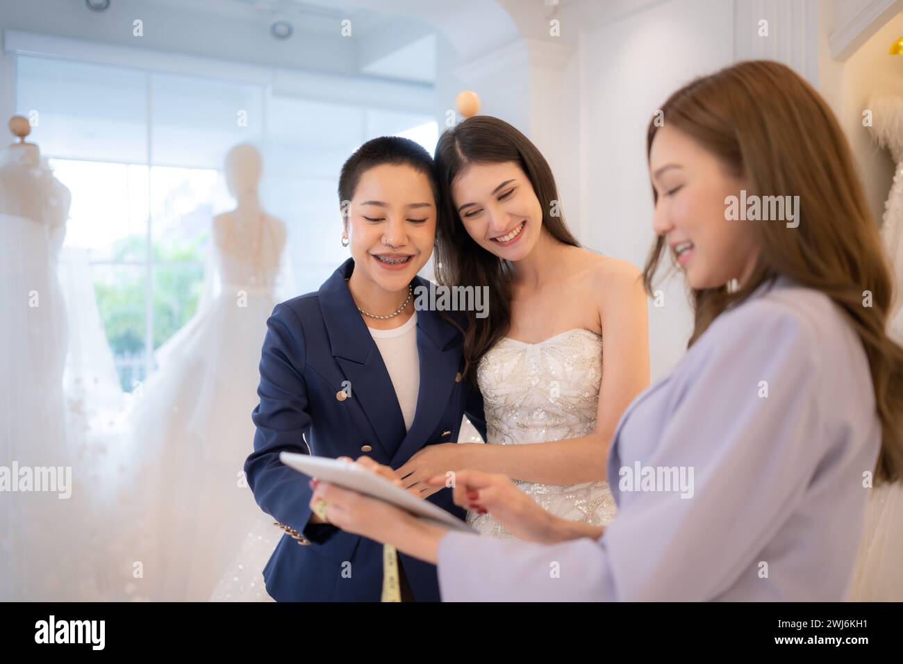 LGBT-Paare entscheiden sich für Hochzeitskleider und Designer beraten sie, wie sie für die Braut geeignet und reizend sind. Stockfoto
